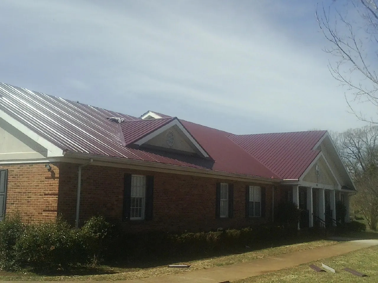 Red metal roof with gabled entries on a long brick building in Arab