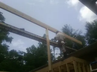 Carpenter setting a ridge beam over a new addition frame — Ice Dam Removal by Roofing Brothers in Arab