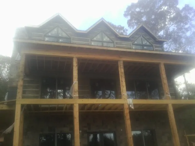 Dormers and porch framing on a large log home under construction — Roof Coating work by our crew in Arab