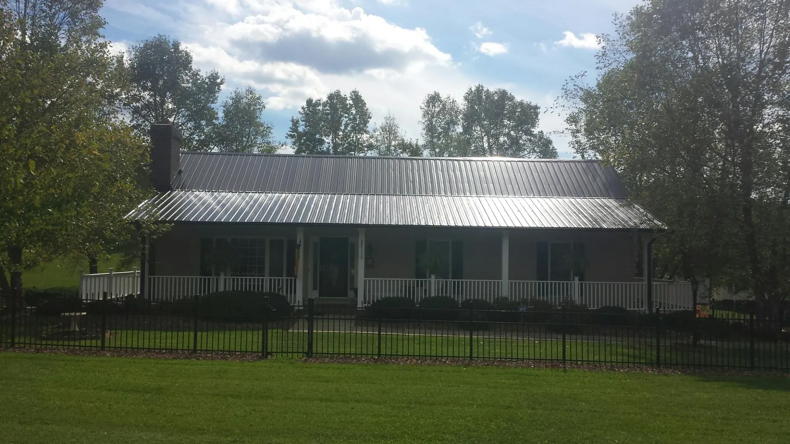 Gray metal roof on a brick ranch with a full width front porch — Gutter Guard Installation work by our crew in Arab