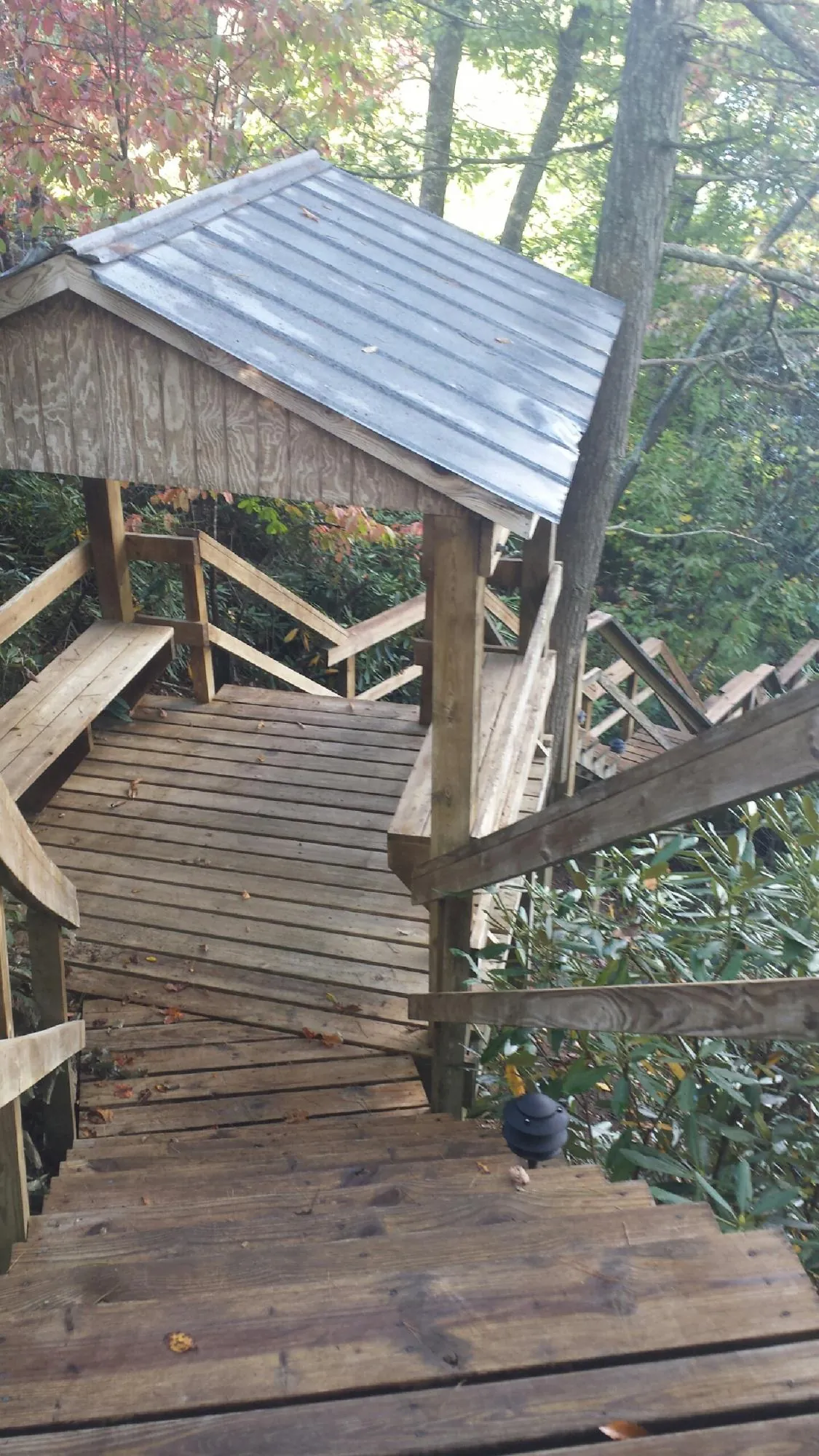 Metal roofed shelter over wooden steps on a wooded walkway — Skylight Repair & Installation work by our crew in Arab