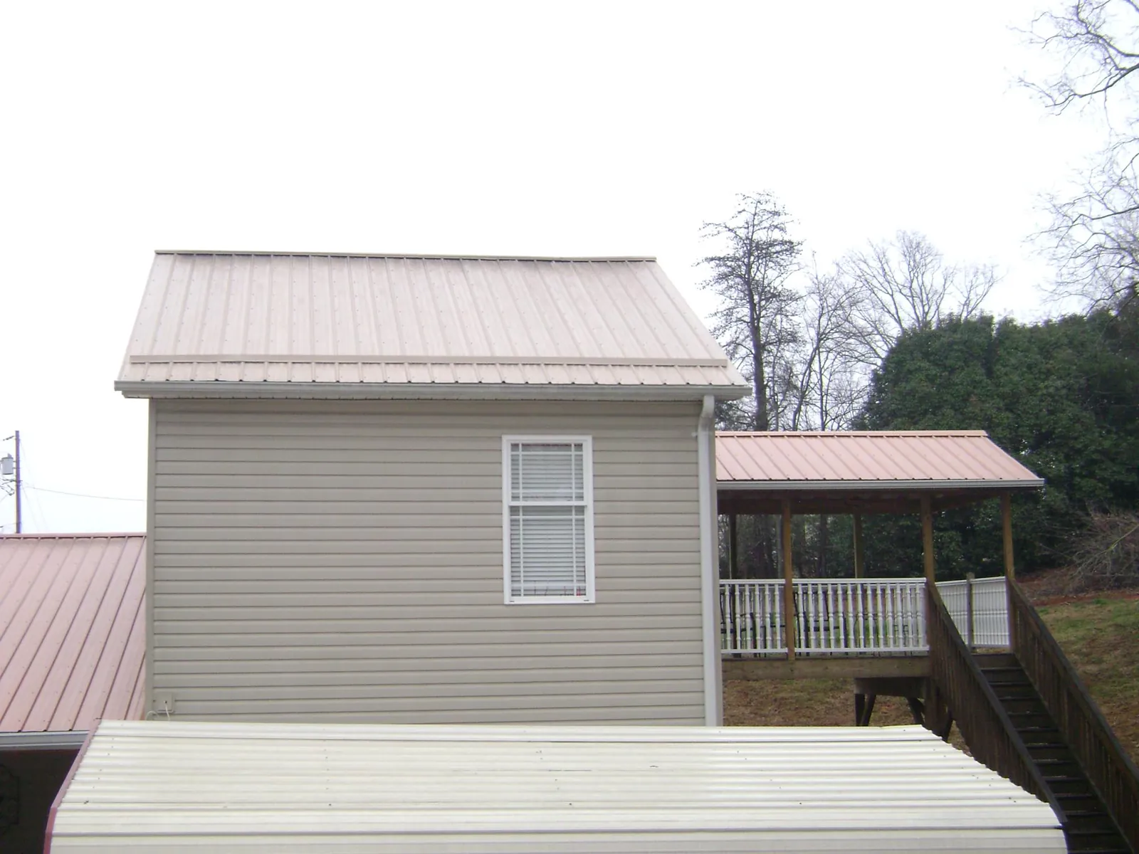 Tan metal roofs on a two story addition and attached porch, from a Roof Replacement job in Arab