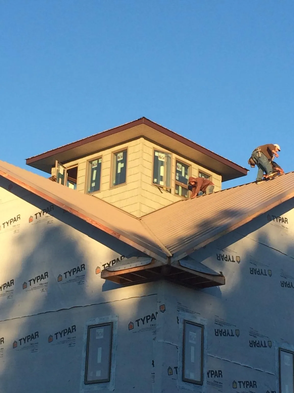 Roofers working around a rooftop cupola on a new metal roof at sunset — Roof Waterproofing in Arab by Roofing Brothers